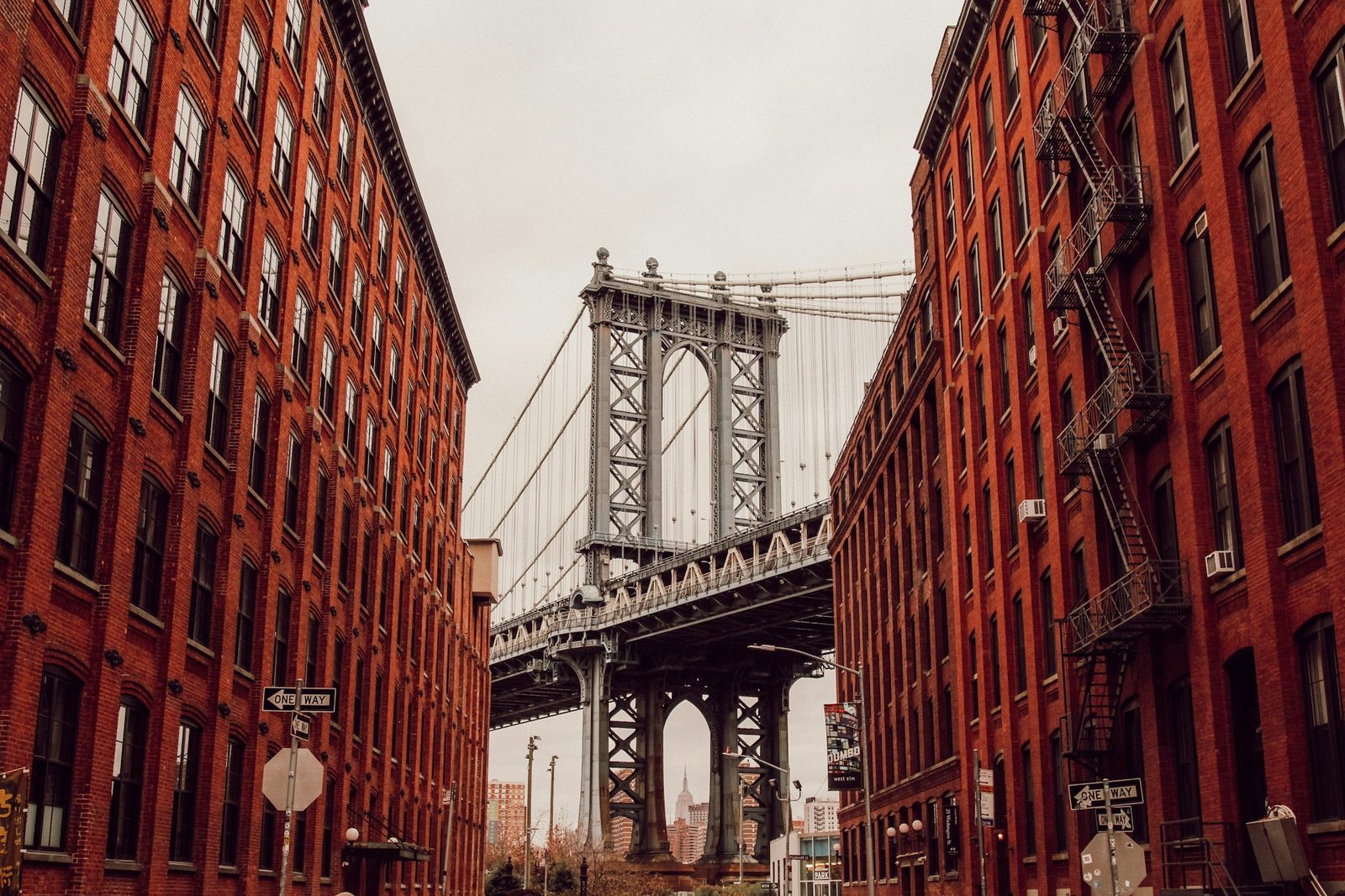 A suspension bridge between two red brick warehouse buildings