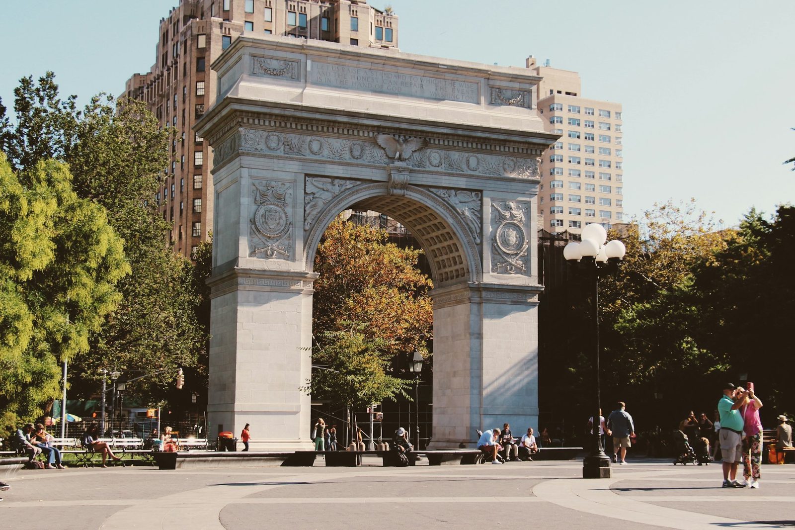 The marble Washington Square Arch with trees and people in the park
