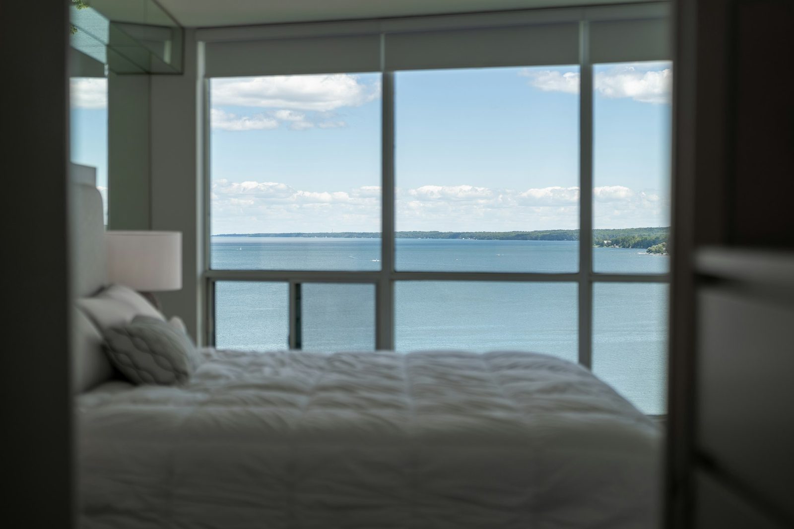 A bed beside a floor-to-ceiling window that looks out across the water.